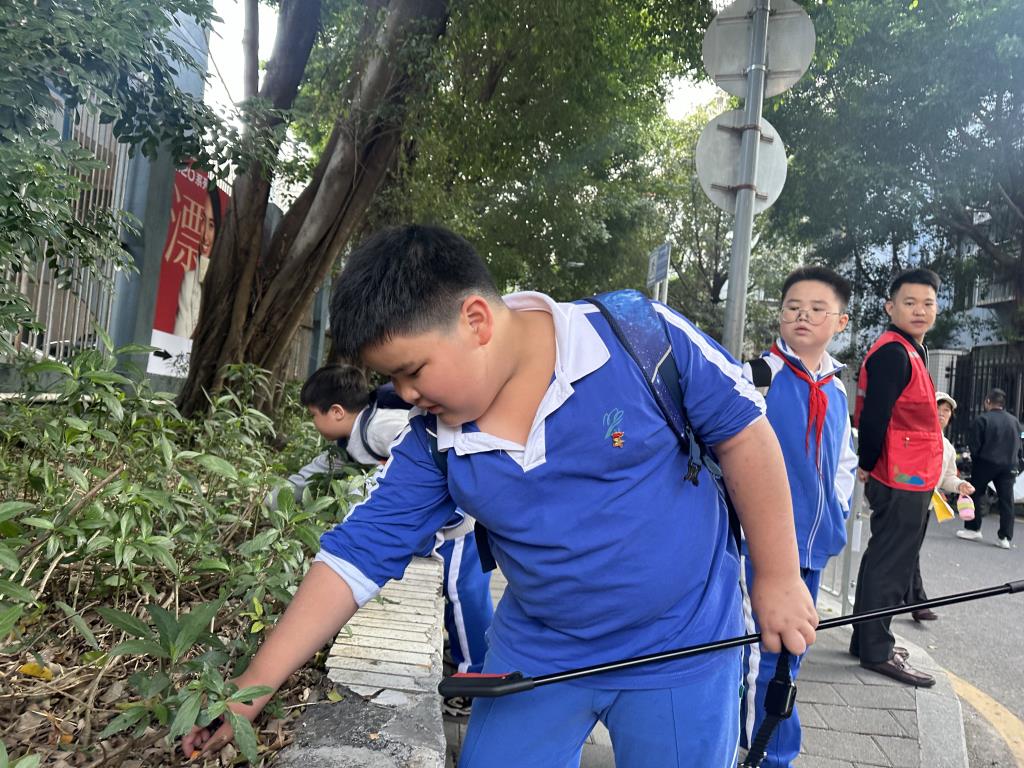 看到老师在夹起垃圾，孩子主动参与进来，用手捡起藏在草丛中的垃