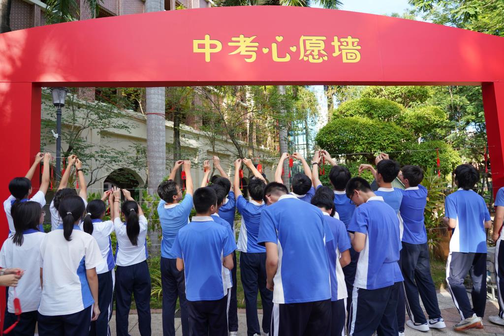 学生将自己的祝福牌系到心愿墙上
